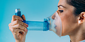 Woman using asthma inhaler with extension tube