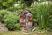 Selbstgemachtes Insektenhotel aus Holz im naturnahen Garten