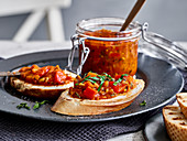 Homemade tomato chutney in a jar and on toasted bread slices