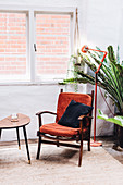 Red upholstered chair by window with view of brick wall