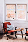 Red upholstered chair by the window with a view of the brick wall