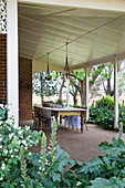 Crockery on wooden table and chairs on roofed terrace