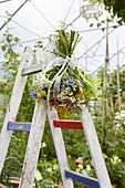 Summer bouquet hung from stepladder in greenhouse