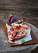 Baguette topped with figs and goat's cream cheese on a wooden board
