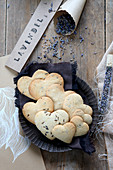 Gluten-free, heart-shaped lavender biscuits next to paper cone and test tube filled with lavender flowers