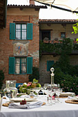 A festively laid table with wine and water carafes in front of a brick facade