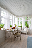 Desk below conservatory windows with airy curtains