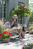 Terrace with stem rose 'Heidi Klum', geraniums and riding grass, woman on bench enjoys the summer