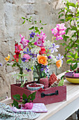 Sommersträuße mit Gladiolen, Rosen, Waldrebe und Wiesenkümmel in alter Schublade, rote Johannisbeeren, Schnur