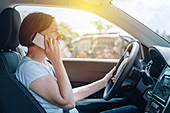 Woman driving car and using phone