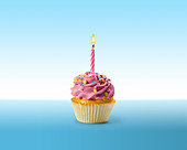 Birthday cupcake with frosting and lit candle