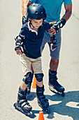 Grandfather teaching grandson to roller skate
