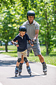 Grandfather teaching grandson to roller skate