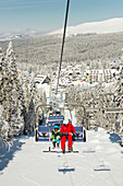 Boy with ski instructor on ski lift