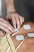 Placing TENS electrodes on upper back