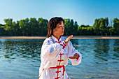 Women practicing tai chi by lake