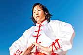 Women practicing tai chi by lake