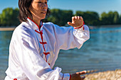 Women practicing tai chi by lake