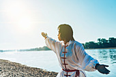 Women practicing tai chi by lake