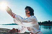 Women practicing tai chi by lake