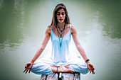 Woman meditating by a lake