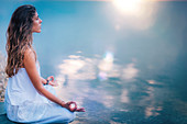 Woman meditating by a lake