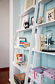 Books and knick-knacks on white angled shelves against pale blue wall