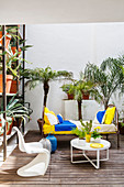 Metal bed used as sofa on summery terrace decorated with palms and cacti