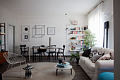 Scatter cushions on sofa, side table and armchair in front of dining area and book shelves
