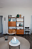 Retro shelving, round rug, classic chair and side tables in living room