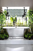 Fabric monkeys above free-standing bathtub and plants on platform