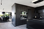 Black, modern kitchen in open-plan interior in shades of grey