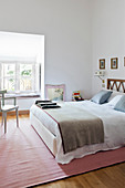 White walls, double bed and pink rug in bright, feminine bedroom
