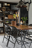 Dining table and black folding chairs in front of rusty metal shelves