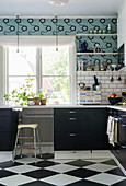 Black kitchen with retro wallpaper and chequered floor