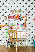 Golden chair at old desk in child's bedroom with horse-patterned wallpaper