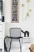 Black metal chair and stacked magazines below old window used as picture frame