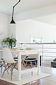 Shell chairs around white dining table next to balustrade of gallery above living space