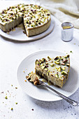 Pistachio cheesecake with white chocolate served on white plate with dessert fork