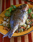 Fried gilthead with young onions and walnuts