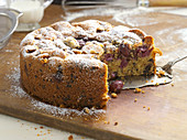 Cherry cake dusted with icing sugar, a piece cut