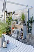 Herbstlich dekorierte Terrasse mit Tisch, Korbstühlen und Holzregal