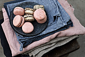 Two kinds of macarons on plates and stacked tablecloths