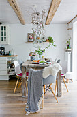 Wooden table, classic chairs and summery arrangement of plants in Scandinavian-style dining room