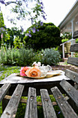 Romantic roses on tray on wooden table next to weathered wooden bench in garden