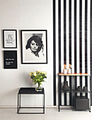 Beistelltisch und Regal vor schwarz-weiß gestalteter Wand mit Streifentapete und Wandbilder