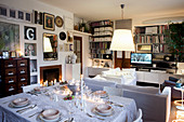 Festively set dining table in living room with fireplace in background