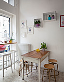 Seating area in window and antique stools around vintage wooden table in small bistro