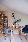 Round table and blue chairs in festively decorated room with sloping ceiling