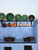 Antique ceramic bowls and old copper pans in country-house kitchen with blue and white tiled surfaces